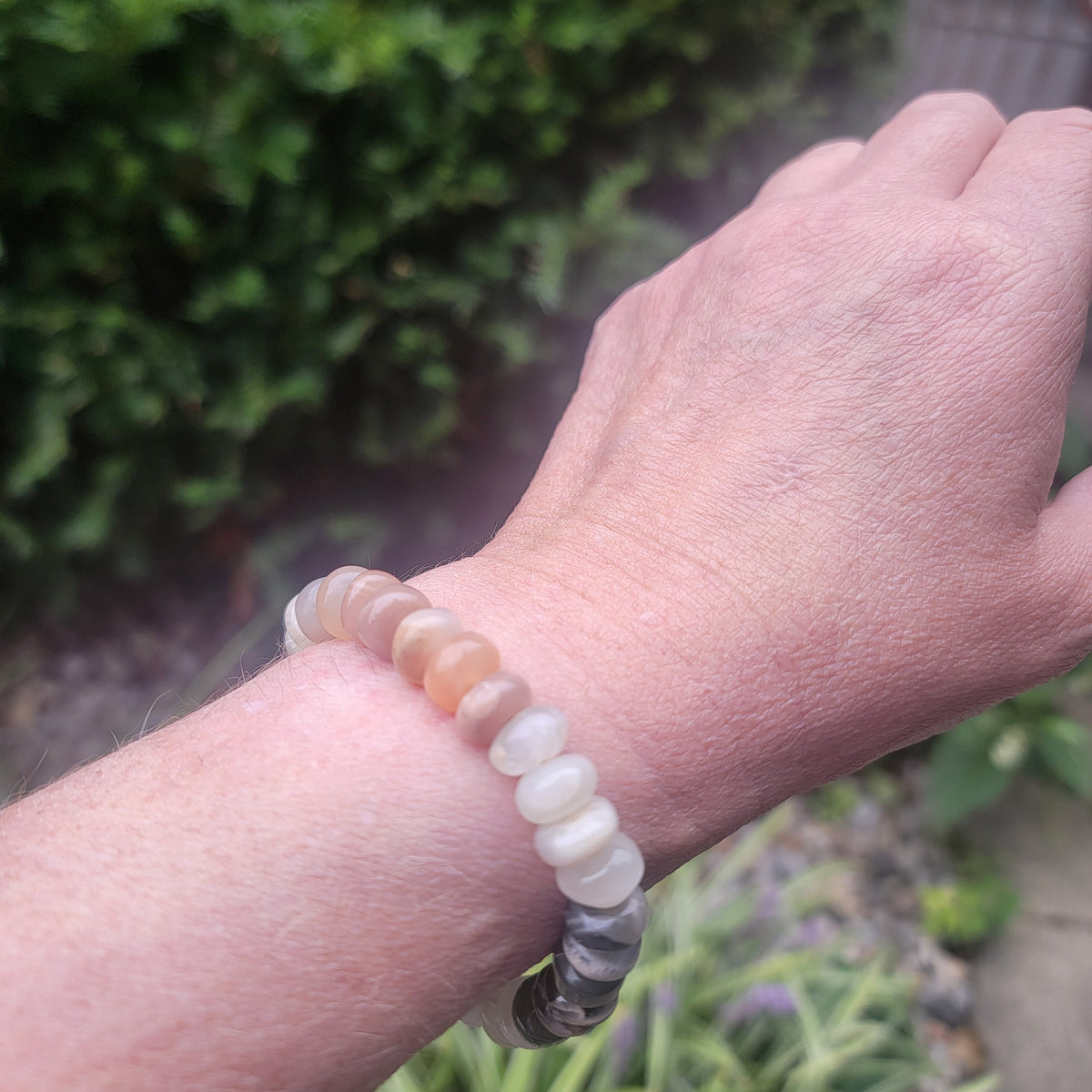 Moonstone beaded bracelet being worn on wrist in natural outdoor environment