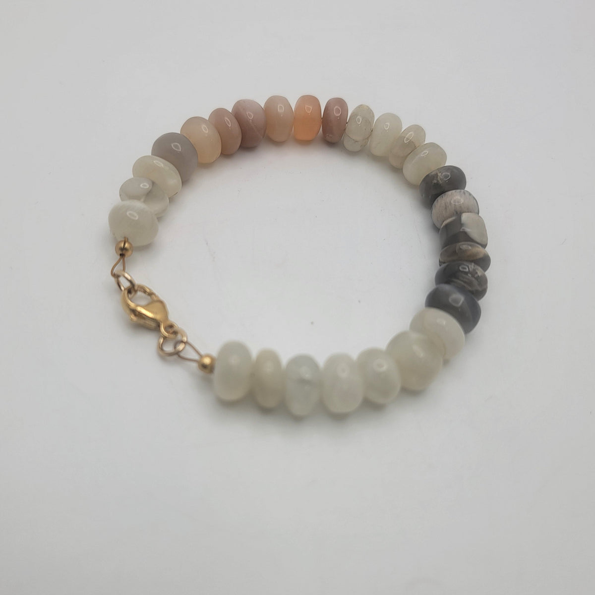 Moonstone beaded bracelet with gold colored clasp on white background